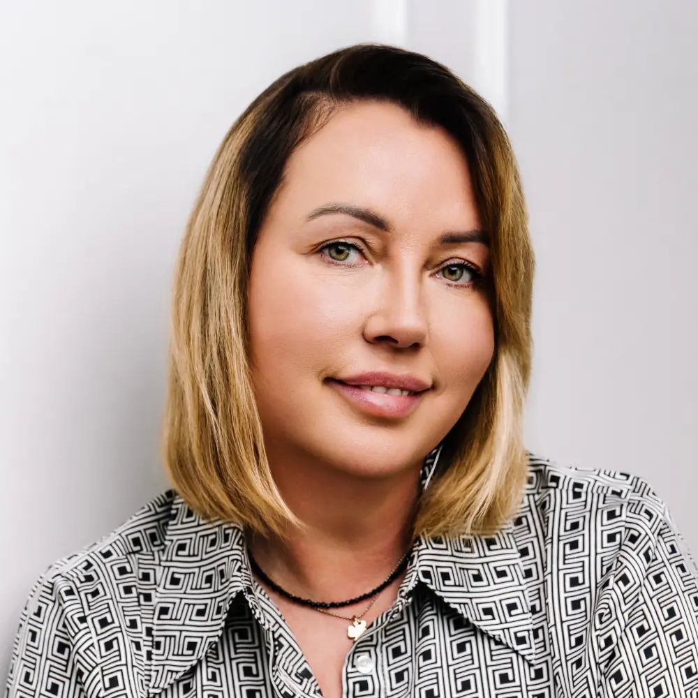 Portret Renaty Ziółkowskiej, terapeutki – zbliżenie na twarz kobiety o blond włosach, w czarno-białej wzorzystej koszuli.